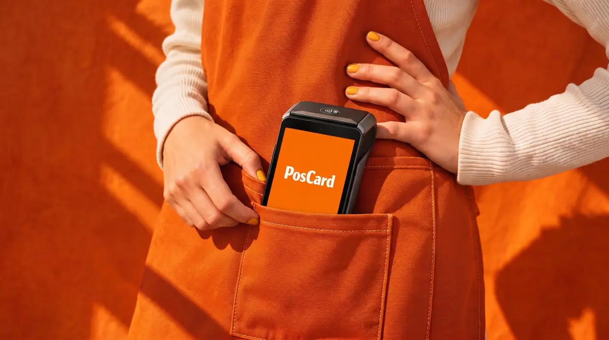 Terminal PosCard asomando del bolsillo de un delantal naranja